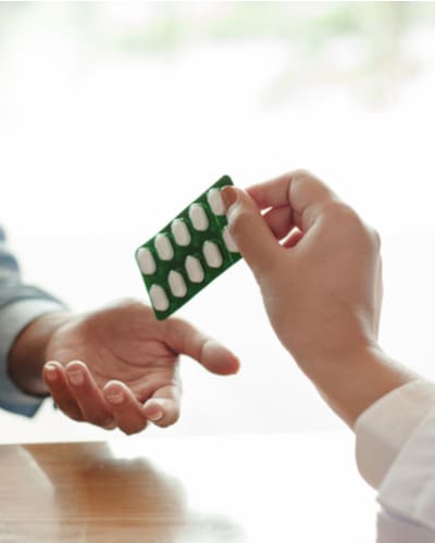 Врач передают пациенту пластинку таблеток